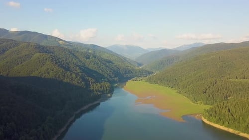 Aerial View of Big Lake with Clear Blue Water Between High Mountain Hills Covered with Dense