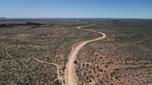 Aerial of Winding Dirt Road in Namibia as SUV Navigates Arid Terrain