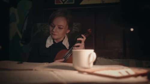 Woman Holds Violin and Writes on Sheet Music
