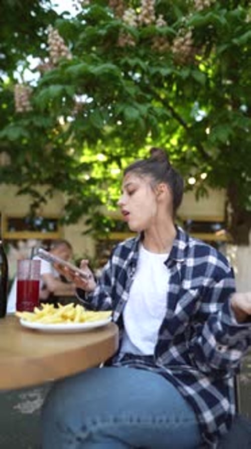 At a Café Terrace a Vibrant Young Lady is Delighting in French Fries on a Summer Day
