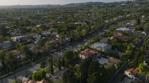 Aerial Slide and Pan Footage of Beverly Hills at Golden Hour Street Lined By Palm Trees and Luxury