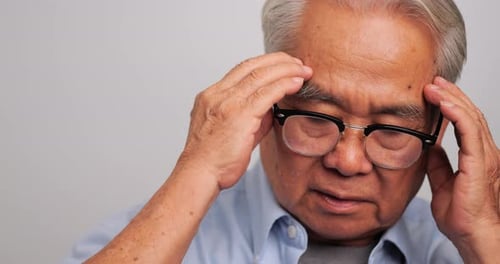 Asian old man with migraine headache. Elderly man suffering from a headache.
