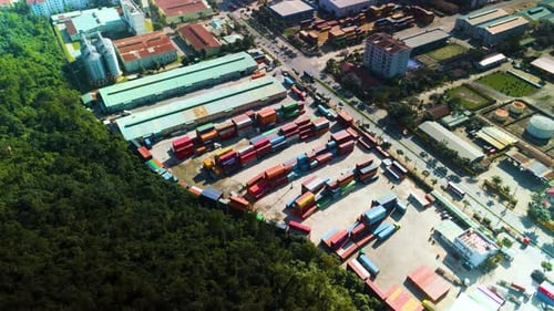 Industrial Zone with Colorful Shipping Containers Bordering a Forest Aerial View Showcasing