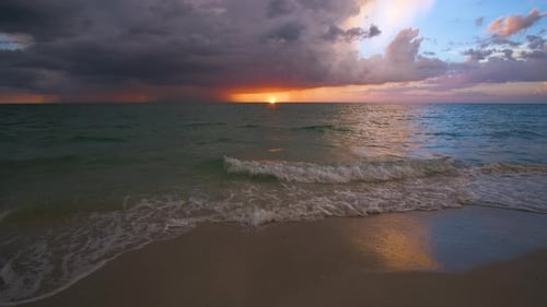 Meereslandschaft mit Gewitterwolken über sanften abendlichen Meerwasserwellen, die am Sandstrand zerquetschen