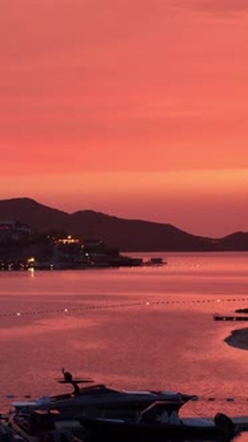 Ville côtière sereine baignée par la lumière chaude d'un coucher de soleil vibrant sur la mer calme