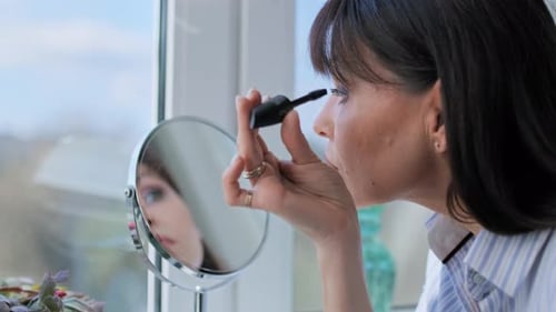 Middle Aged Woman Doing Makeup Applying Mascara Looking in Mirror