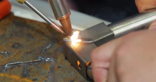 Laser welding machine with hand hold gun. Laser welding is shown in close-up.