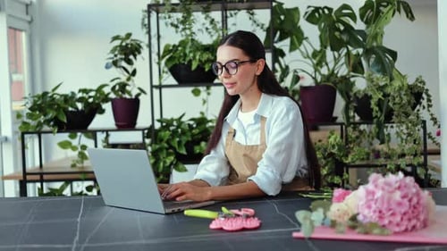 Woman Typing on Laptop Surrounded by Plants