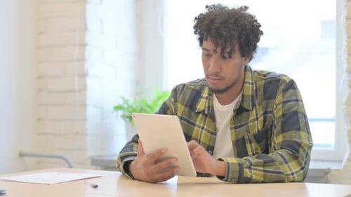 Adult Man Using Tablet at Table Indoors