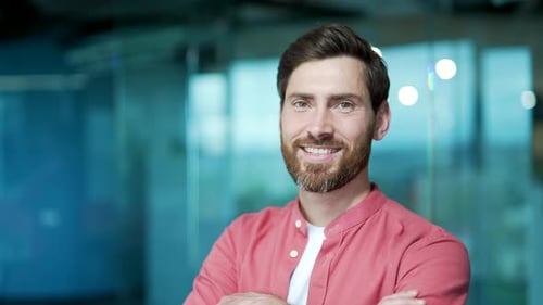 Close up portrait of positive friendly bearded businessman worker looking at the camera at modern
