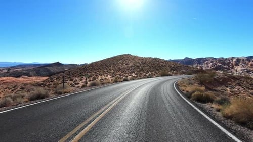 POV: Driving along an empty road through stunning Arches National Park in Utah on sunny day. Curvy r