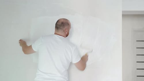 Man Painting Wall with Roller Indoors