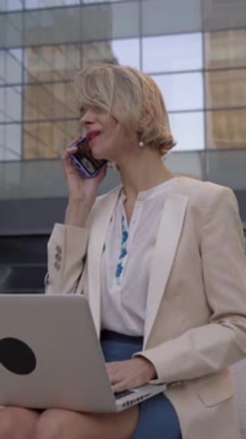 Femme d'affaires caucasienne travaillant à l'extérieur utilisant un ordinateur et un mobile pour être connectée à tout moment