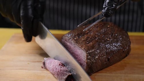 Chef Slices Roast Beef with Knife and Fork