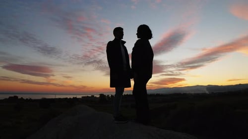 Silhouetted Couple Embraces in Sunset Near Ocean