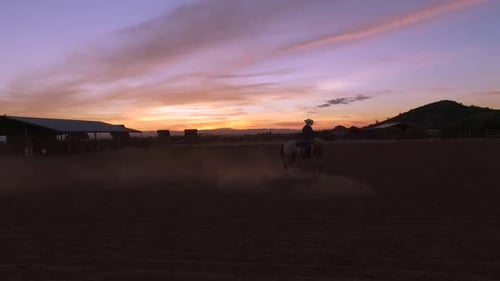 As the Arizona sunsets, a cowboy is still working his horse in the corral, Queen Creek, Arizona