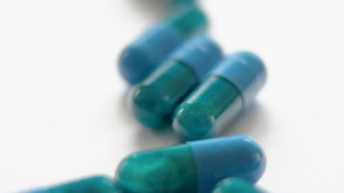 very bright vertical close-up from top to bottom of dark blue and green capsules on a white surface