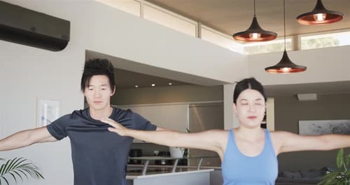 Casal chinês iniciando a rotina, levantando, estendendo os braços, vestindo roupas de ginástica para ioga em casa em tapetes