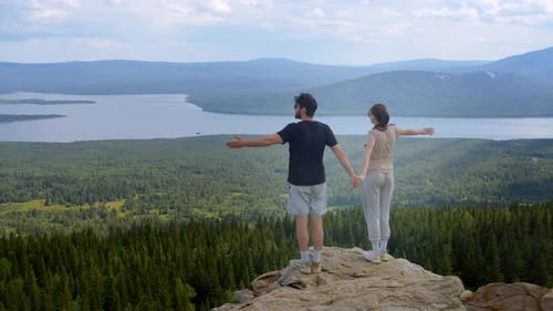 Dos amantes subieron a la cima de la montaña y ahora disfrutan de la belleza y la libertad del