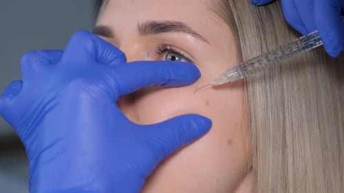Woman in Beauty Salon Getting Botox Injections to the Cheek Close Up Smoothing of Periorbital