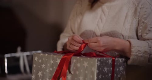 Woman Untying Red Ribbon on Christmas Gift
