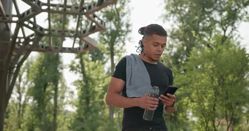Athletic Man Uses Phone After Workout in Park