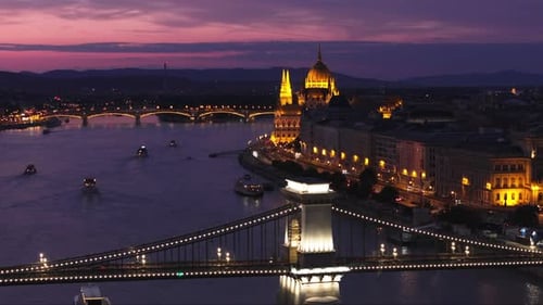 Szechenyi Chain Bridge and Beautiful Historic Building of Hungarian Parliament at Night Illuminates