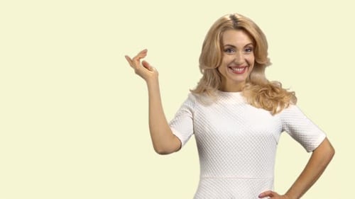 Glückliche, fröhliche blonde Frau, die mit ihrem Zeigefinger auf den Copy Space zeigt