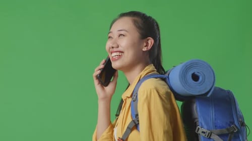 Side View Of Female Hiker Talking On Smartphone And Looking Around While Walking On Green Screen