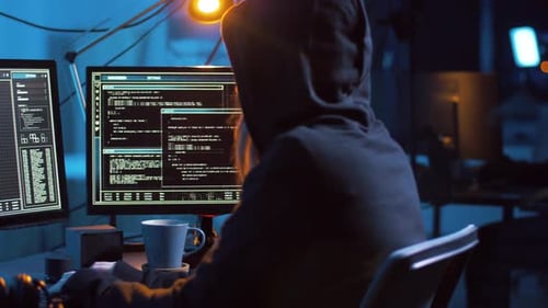 Hooded Hacker Types at Computer in Dark Room