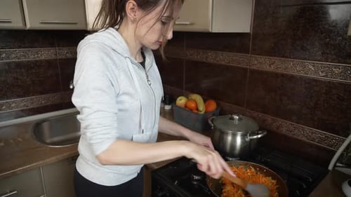 Woman Cooking Food in Pan on Stove
