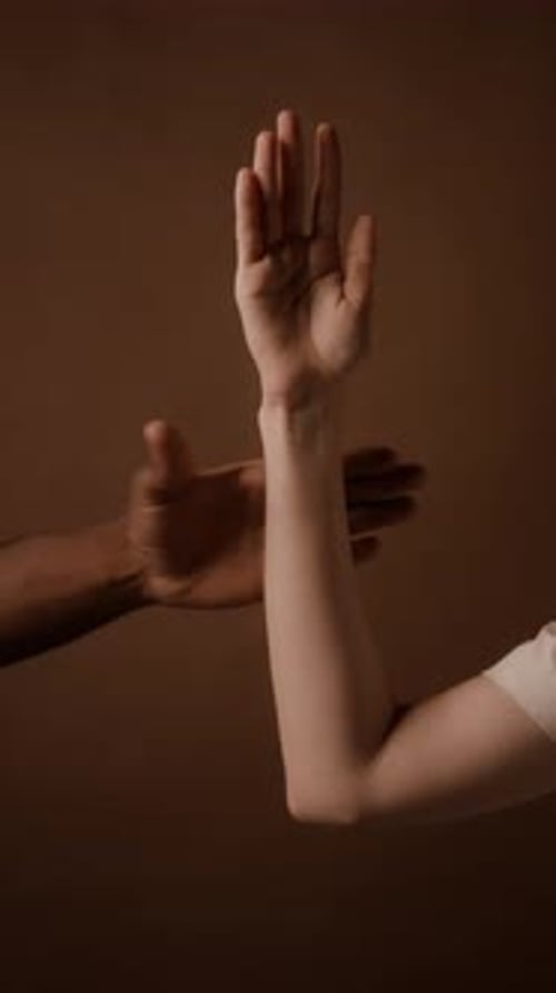 Man Grasping Wrist of Woman Holding Bent at Elbow Arm up