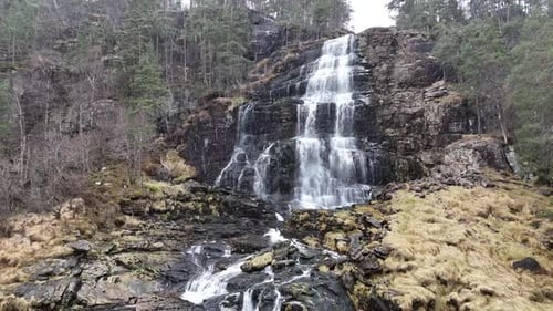 Majestic Waterfall Cascading Down Rocky Hillside in Wilderness