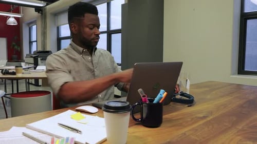 Businessman with Headphones Working at Laptop in Open Plan Office 3034 Years