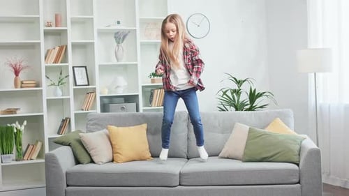 Girl Energetically Dancing on Couch in Bright Home