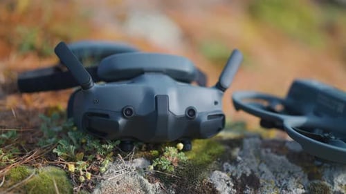 FPV drone goggles near aircraft on outdoor surface with rock and grass