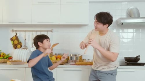 Father and Son Dancing with Spoons in Kitchen