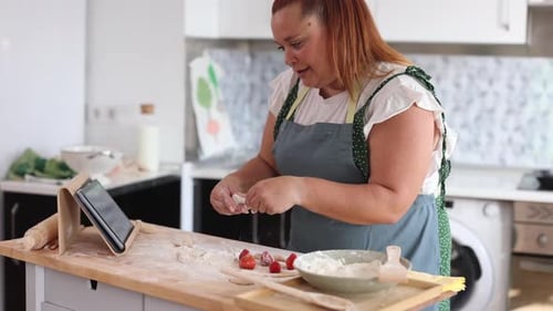 Woman Prepares Food at Kitchen Counter With Tablet