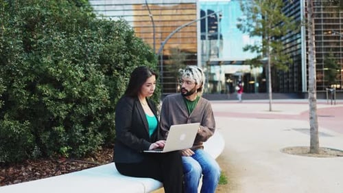 Business people sitting outside the office having a business meeting and using a laptop computer