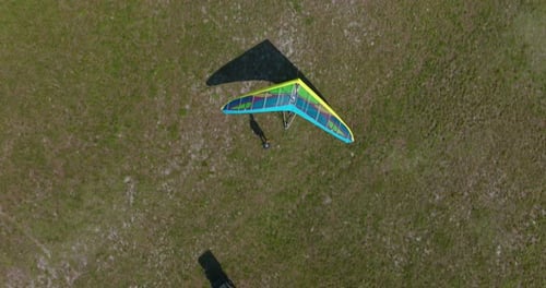 Drone shot - Overhead view as takes off towing behind an ultralight, camera tilts up