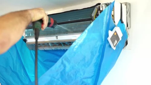Man Cleaning Air Conditioner with Water Spray