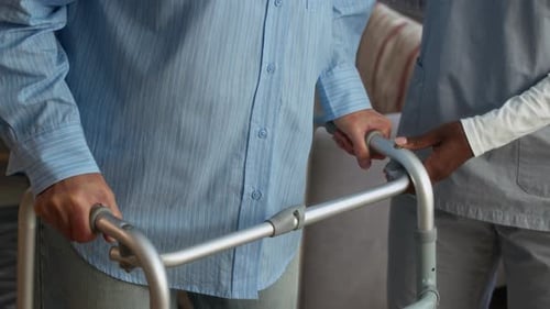 Close Up of Caregiver Assisting Senior with Walker