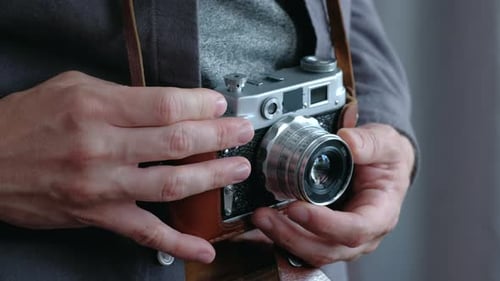 Man Holds and Adjusts a Vintage Film Camera