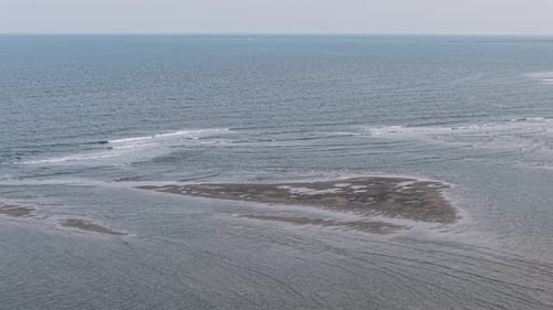 Aerial view of a small tidal island surrounded by ocean waves off the coast of South Carolina