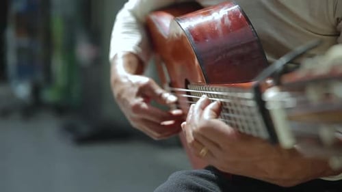 Un músico callejero que toca hábilmente una guitarra acústica de cuerdas de nylon.