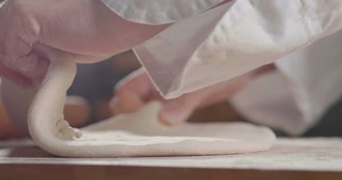Close up of a baker kneading with his hands to prepare the bread to put in the oven. Concept of: a
