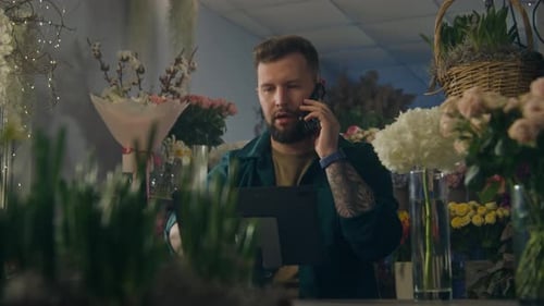 Male Florist Talks By Phone with Customer and Takes Order Using Digital Tablet