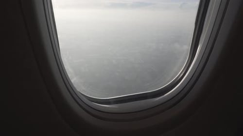 4K shot reveal upwards of the view of a flying plane passenger through the window seeing fields and