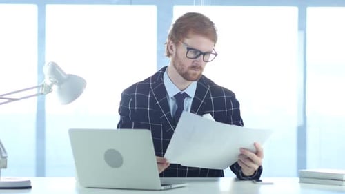 Redhead Businessman Reading Documents in Office Study