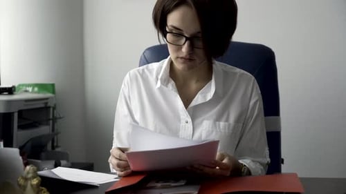 Office Worker Reviews Paperwork at Her Desk